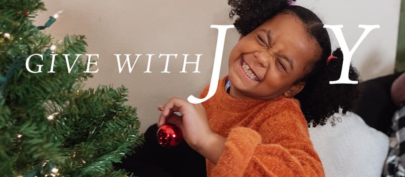 Give with Joy text with young girl smiling face as O in Joy