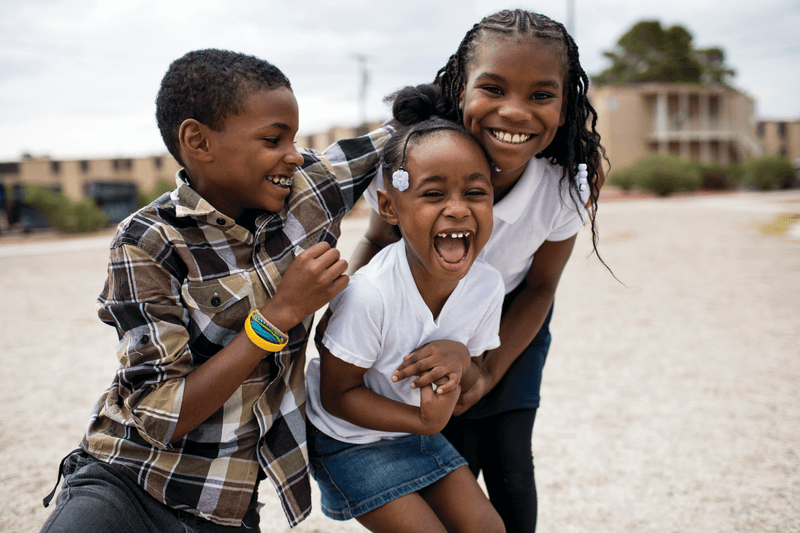 Children playing and hugging together outside.
