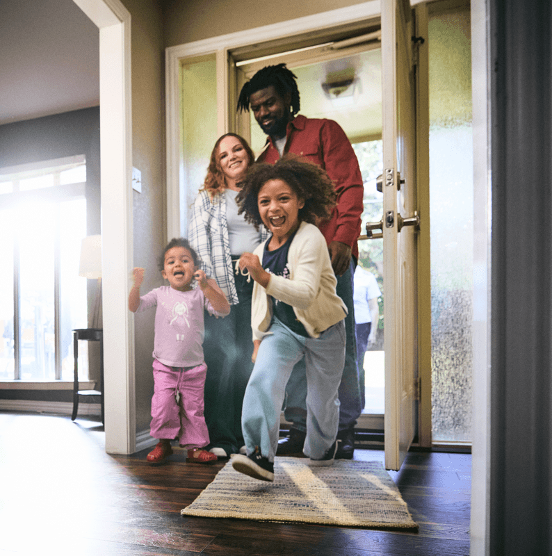 Family running in the front door of their home.