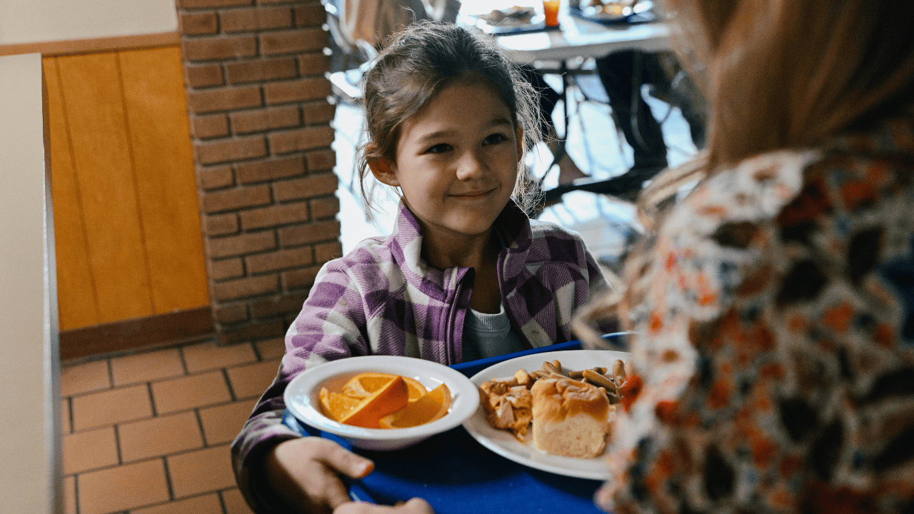 Little girl being served with food by a woman