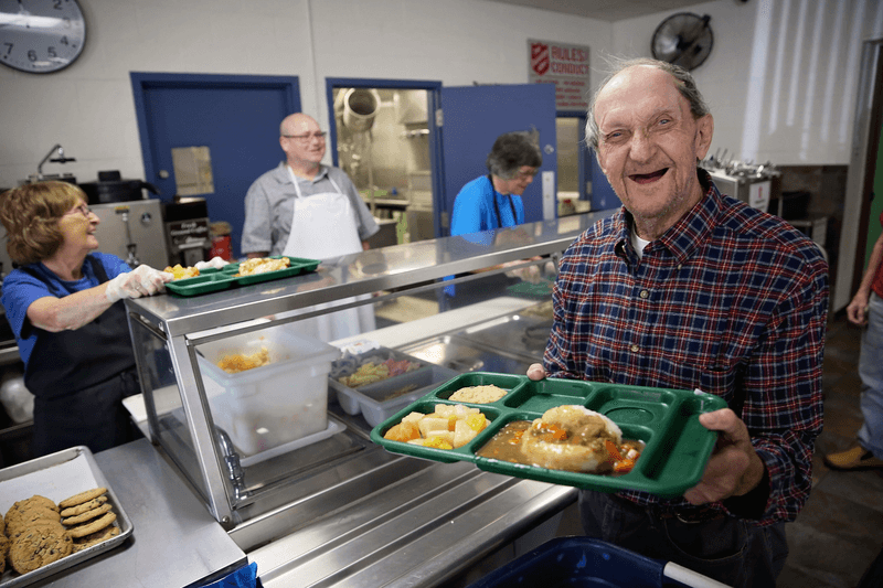 A senior man smiling holding a tray with food