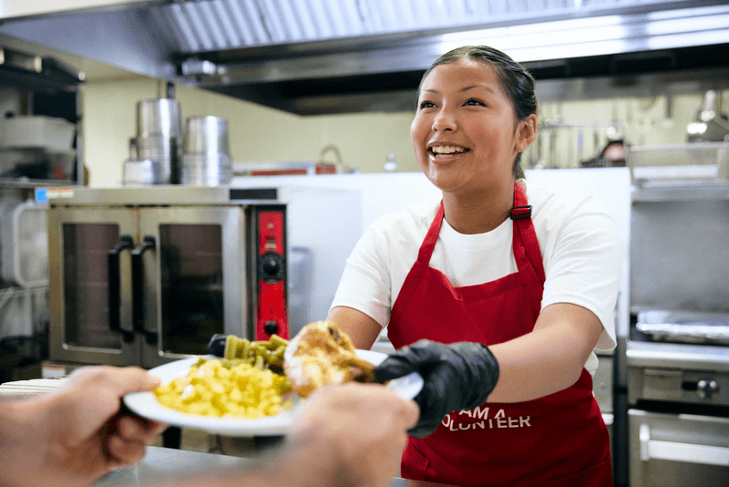 Volunteer serving food to neighbor in need at The Salvation Army feeding program.